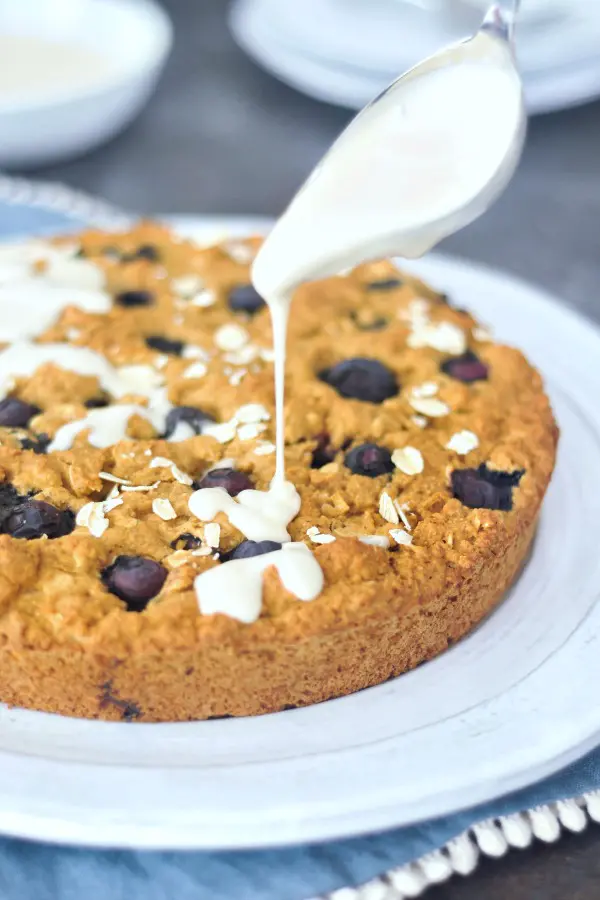 yogurt glaze being spooned over Blueberry Breakfast Cake