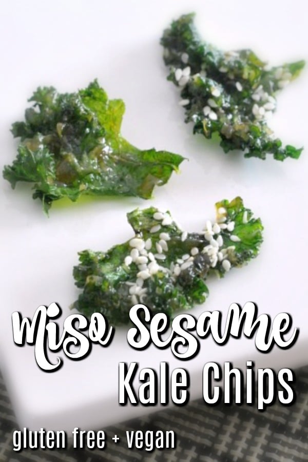 Crispy kale chips with sesame seeds served on a white ceramic platter.