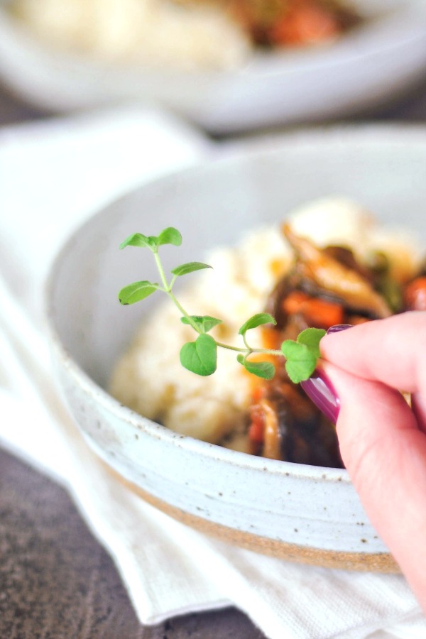 placing a fresh green sprig of thyme on a bowl of mushroom stew
