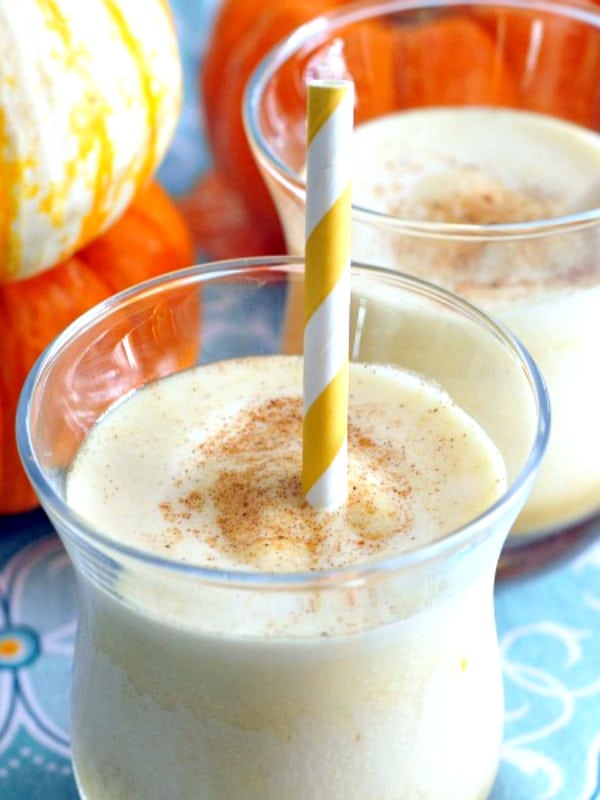 light yellow pumpkin smoothie with cinnamon sprinkled on top and a yellow striped straw