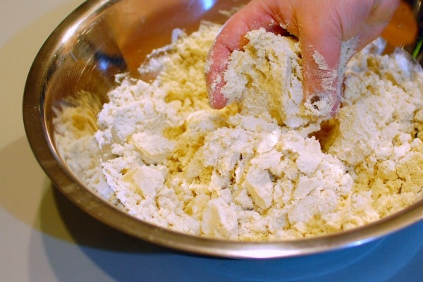 how to make masa: a large silver bowl of masa being blended by hand