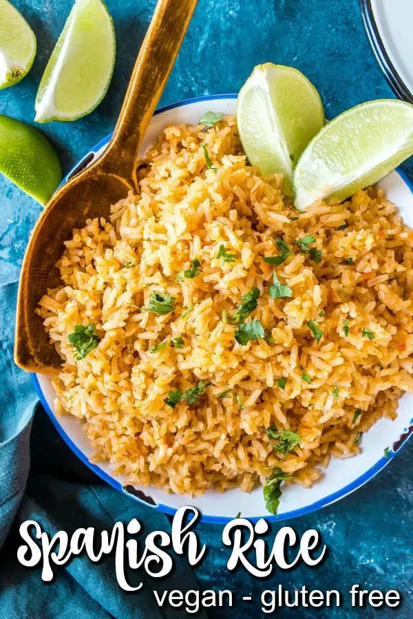 overhead view of serving bowl of Spanish Rice garnished with cilantro and lime wedges