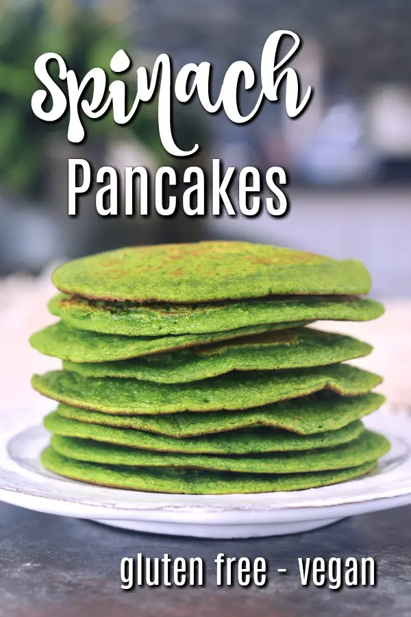 a stack of bright green spinach pancakes on a white rustic plate.