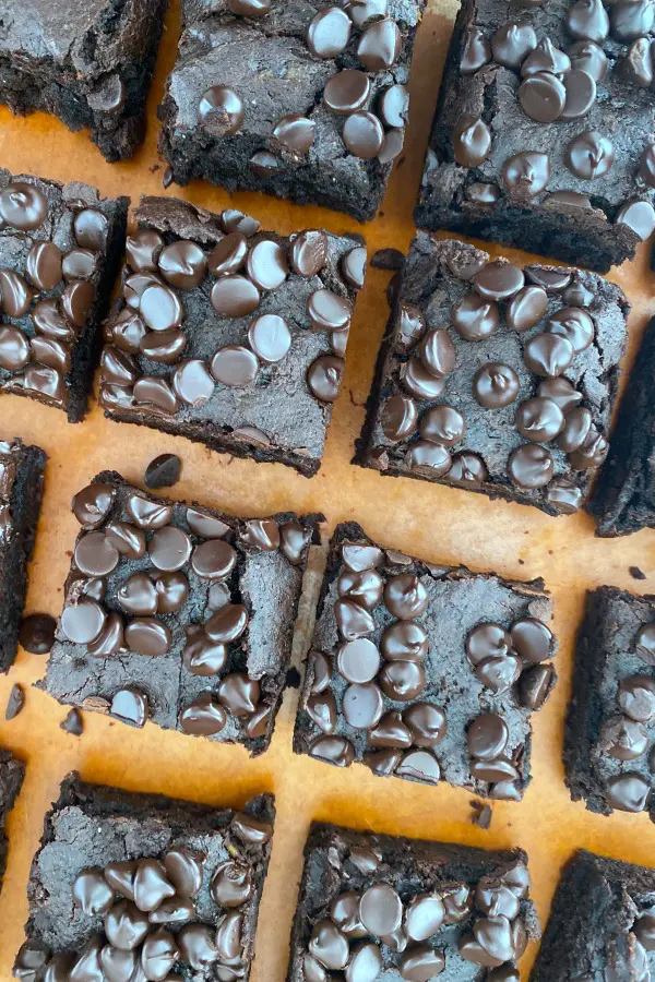 overhead image of sweet potato brownies topped with chocolate chips, cut into squares on a cutting board