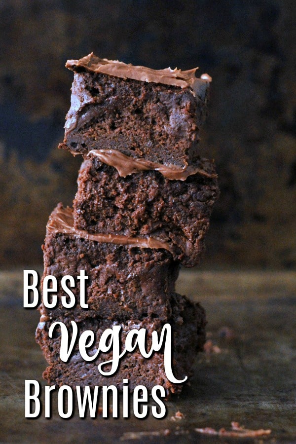 a stack of four frosted vegan brownies against a dark marbled background, the text of " the best vegan brownies" in lower left corner