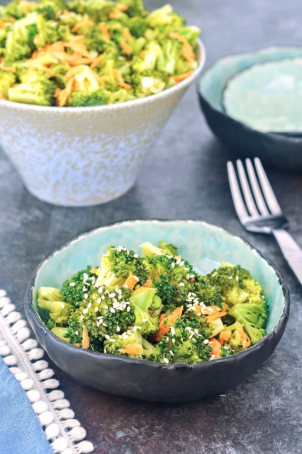 a rustic bowl with a portion of broccoli salad, larger serving bowl of sala...