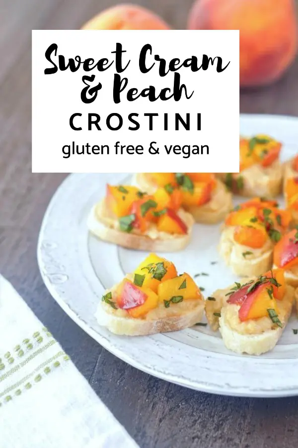 light grey plate of sweet cream peach crostini topped with chopped basil leaves, two fresh peaches in background