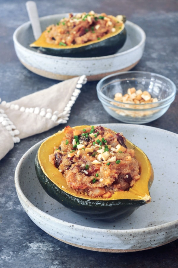stuffed acorn squash: an amaranth grain mixture stuffed into a half an acorn squash, served in a grey rustic shallow bowl, topped with cashews and chives