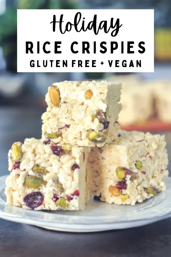 a stack of vegan holiday rice crispies - marshmallow treat squares filled with deep red dried cranberries and bright green pistachios