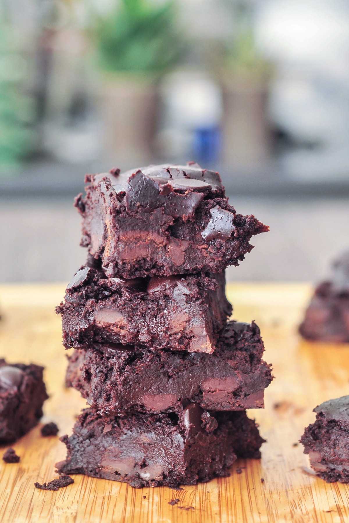 a stack of four chocolate black bean brownies on a light tan bamboo cutting board