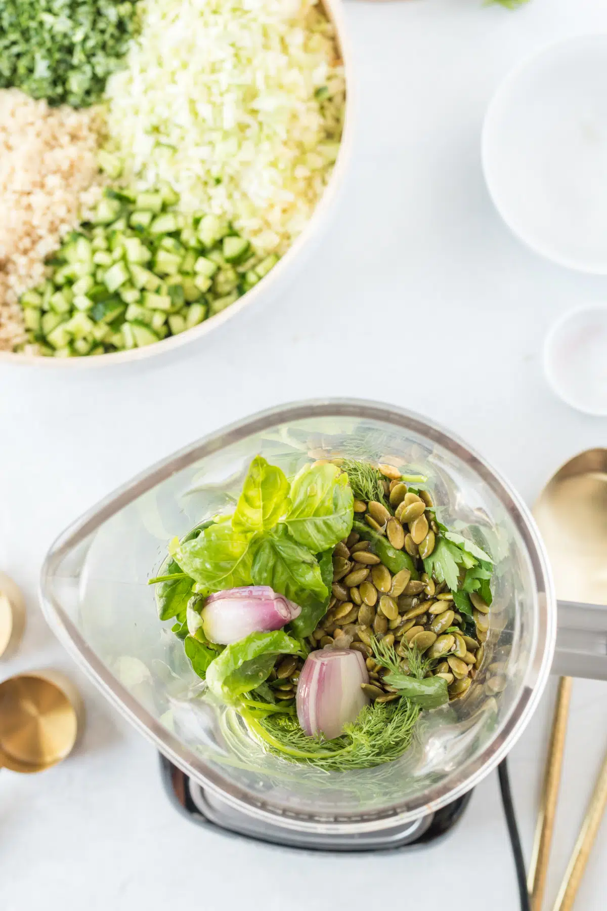 overhead view of green goddess dressing ingredients in a blender jar before blending: fresh basil, dill, shallots, pumpkin seeds, parsley...