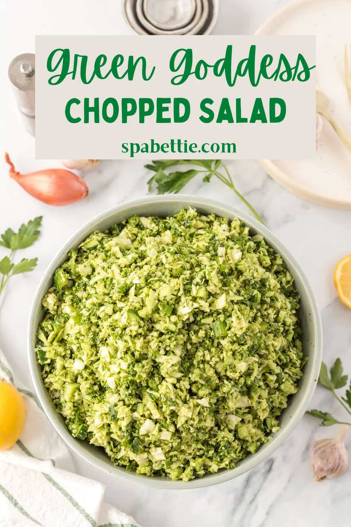 overhead view of green goddess chopped salad: a white bowl filled with finely chopped cabbage, cucumbers, green onions, kale, and cooked quinoa with a bright herby green goddess dressing.