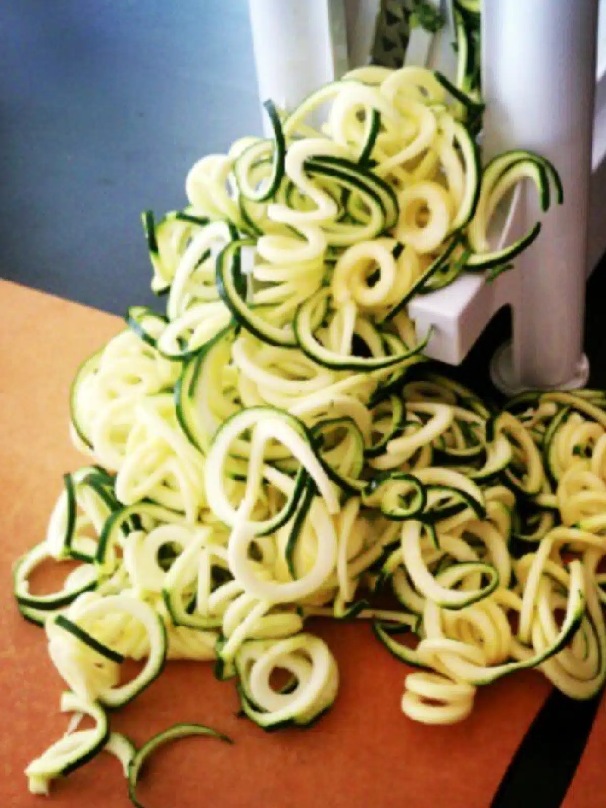 zucchini spirals coming out of the white spiralizer machine.