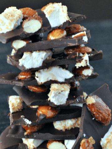 Caramelized Almond Rocky Road Bark pieces in a stack (chocolate, candied almonds, marshmallow pieces)