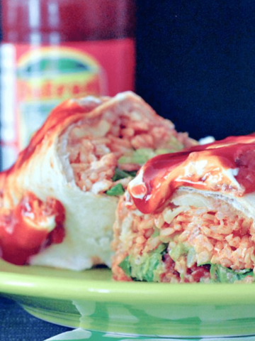 a homemade version of a Honkin' Huge Burrito, Portland's best food cart for 25 years. a large burrito sliced in half to show ingredients: beans, rice, greens, cheese, and sweet saucy stewed tomatoes on top.