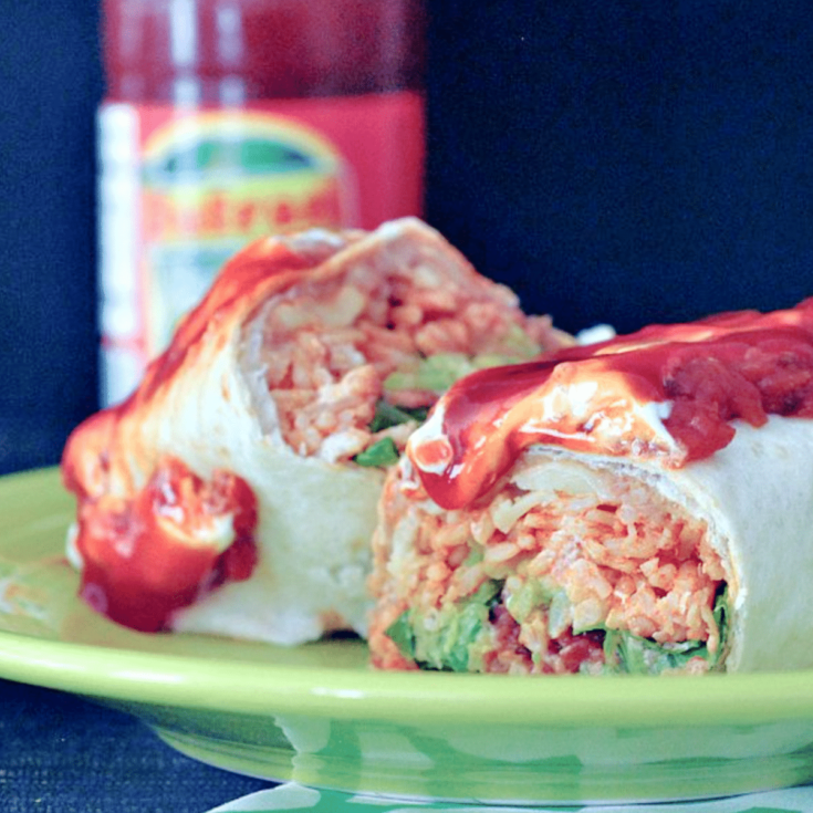 a homemade version of a Honkin' Huge Burrito, Portland's best food cart for 25 years. a large burrito sliced in half to show ingredients: beans, rice, greens, cheese, and sweet saucy stewed tomatoes on top.