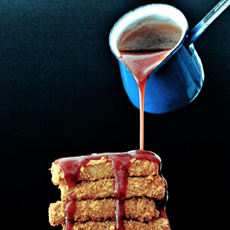 a gluten free vegan BBQ sauce being poured from a blue sauce ladle onto a stack of fried tofu slabs.