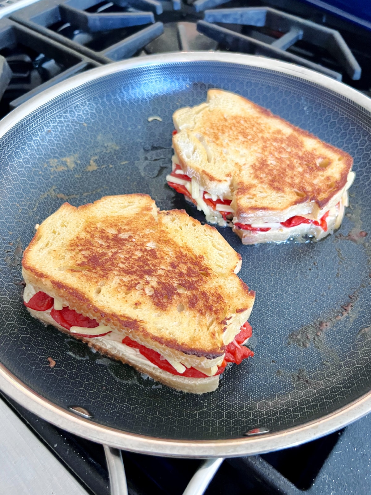 two roasted red pepper grilled cheese sandwiches cooking in a skillet