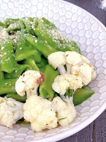 bright green mac and cheese with roasted cauliflower in a shallow pasta bowl