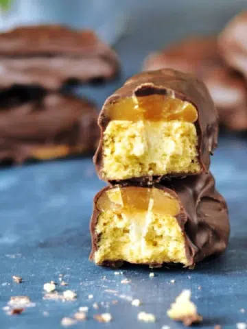 a Twix candy bar broken in half to see the caramel and cookie inside.