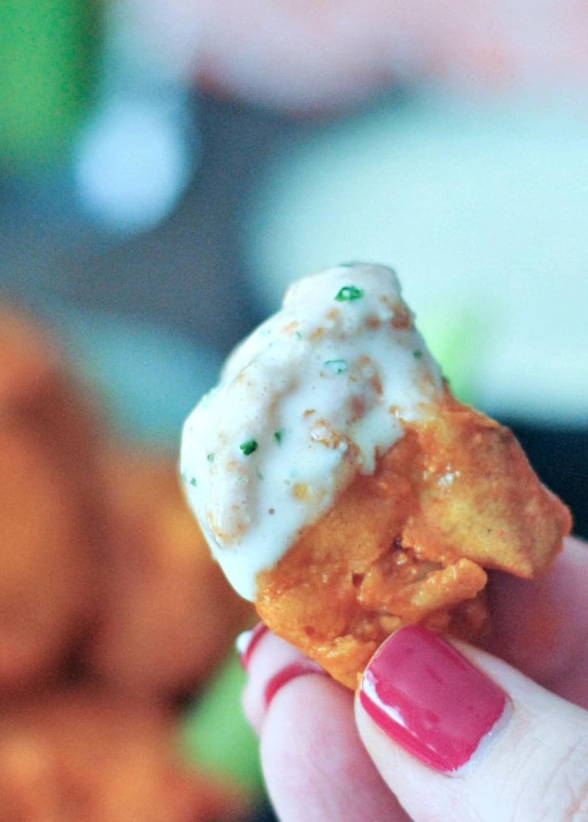 A hand holding a single piece of air fryer buffalo cauliflower dipped in ranch dressing.