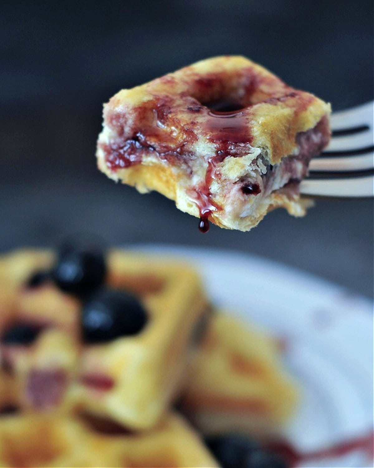 One bite of Luxardo cheesecake stuffed waffle on a fork, showing cheesecake filling inside.