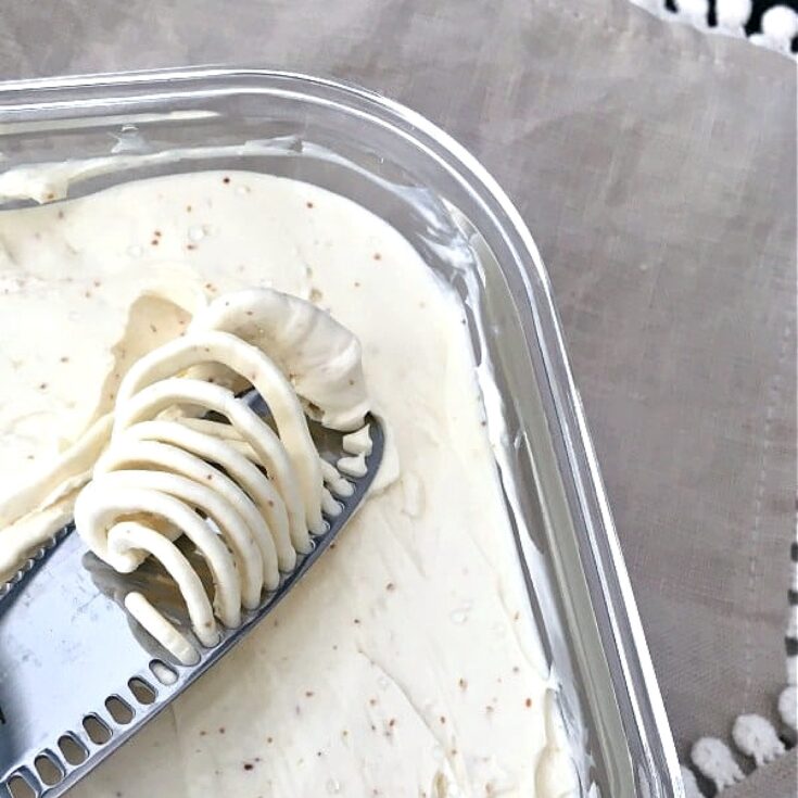 vegan butter in a square glass container, a butter knife spreading a dollop of butter across the surface.