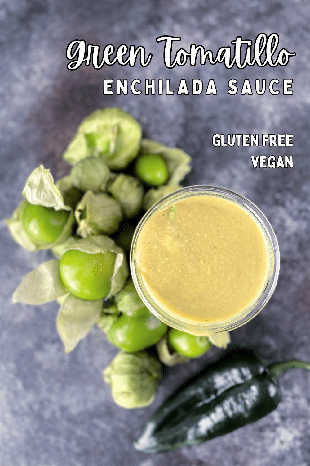 Overhead view of homemade green tomatillo enchilada sauce in a glass canning jar, surrounded by whole fresh tomatillos and peppers.