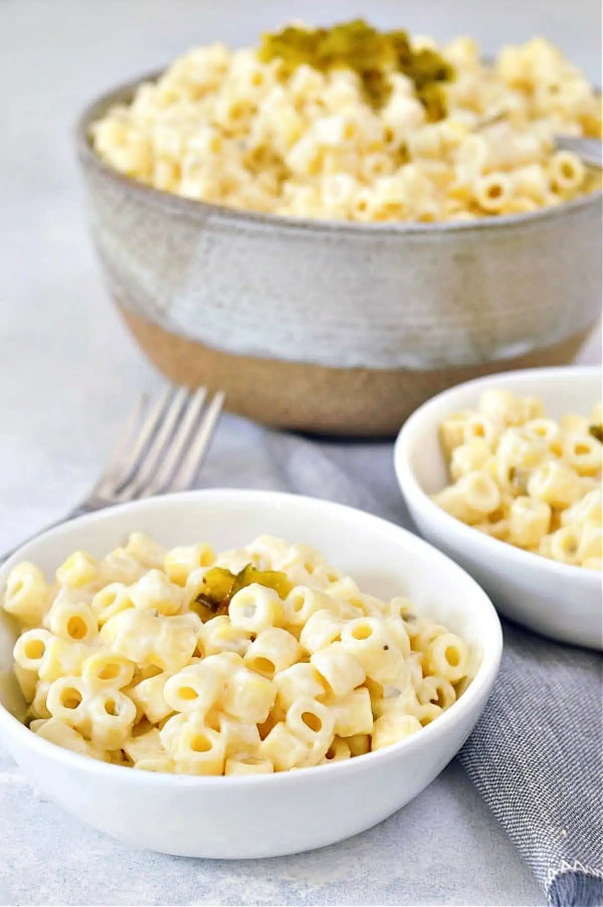 Hawaiian mac salad in a grey serving bowl, with two smaller bowls of mac salad on the side.