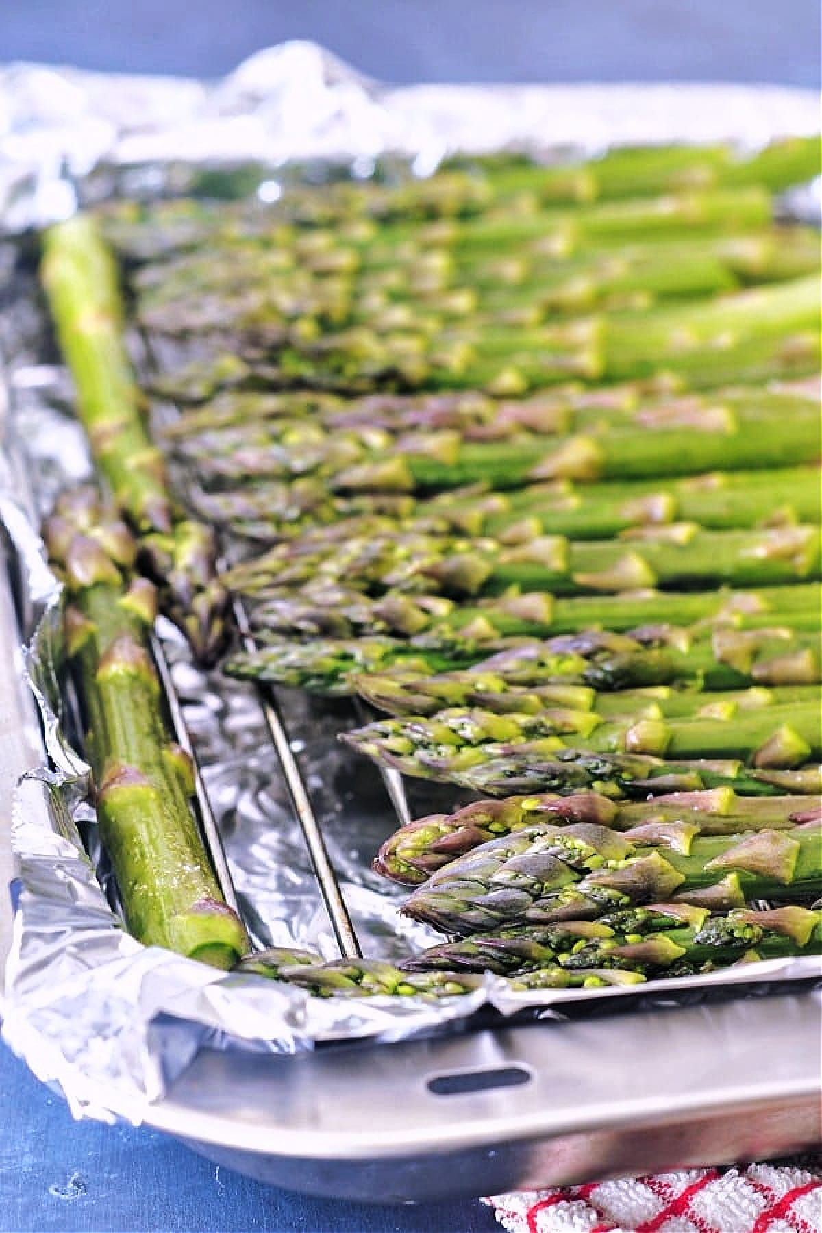 fresh asparagus arranged in a single layer on a foil lined baking sheet, showing how to roast asparagus.