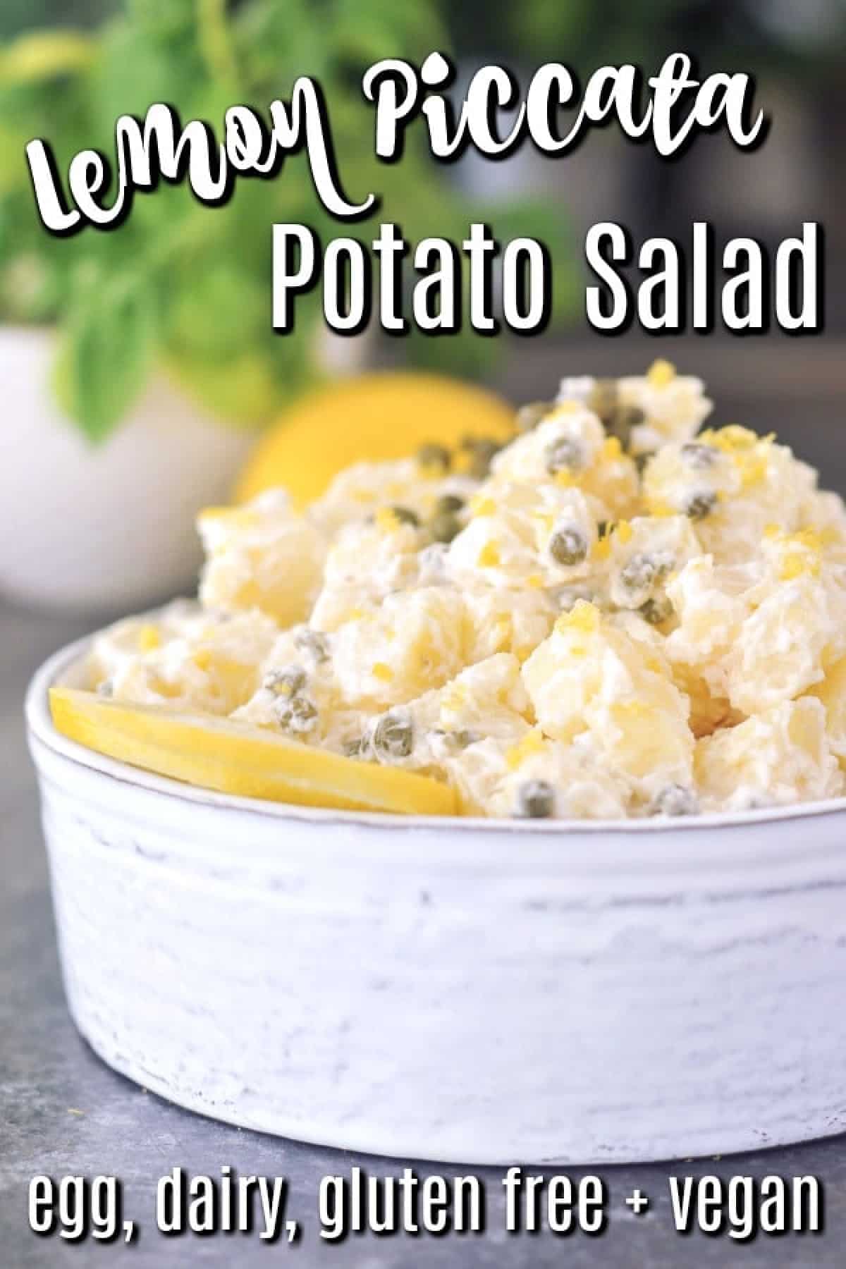 Lemon piccata potato salad in a serving bowl, garnished with a lemon slice, lemon zest, and capers