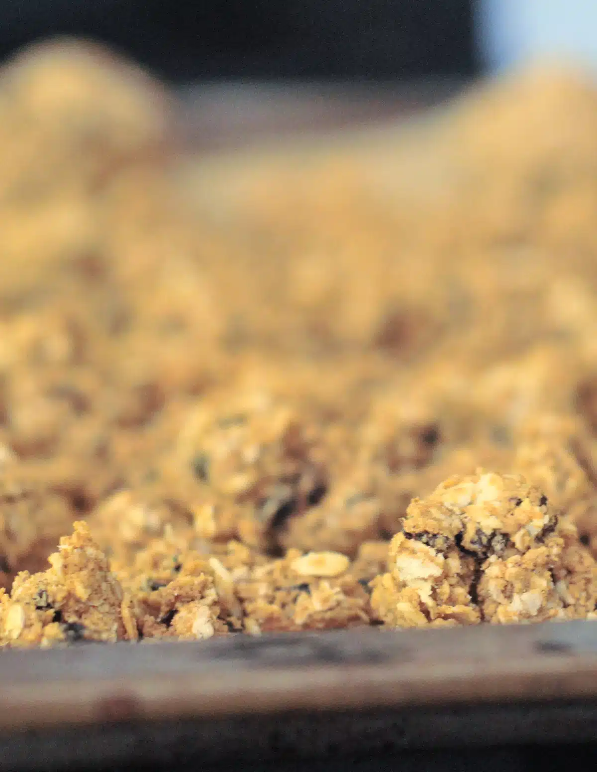 Close up of oatmeal raisin cookie granola on a baking sheet.