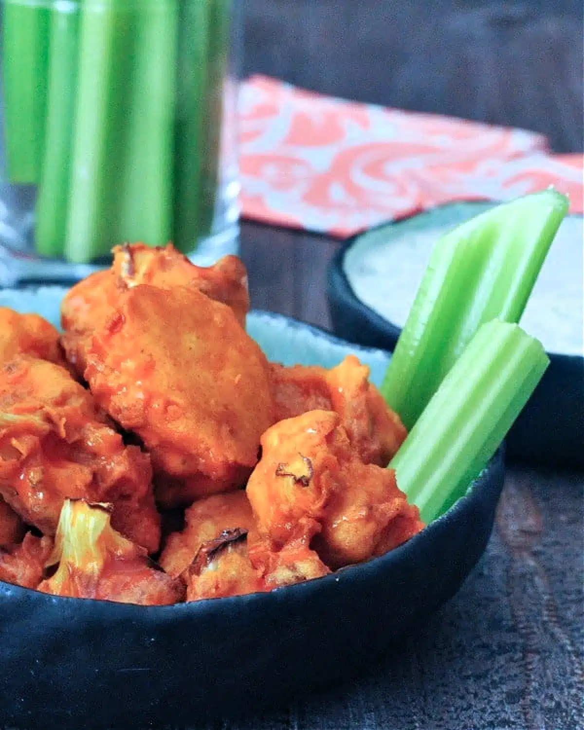 Vegan air fryer buffalo cauliflower served in a bowl with celery and ranch dressing on the side