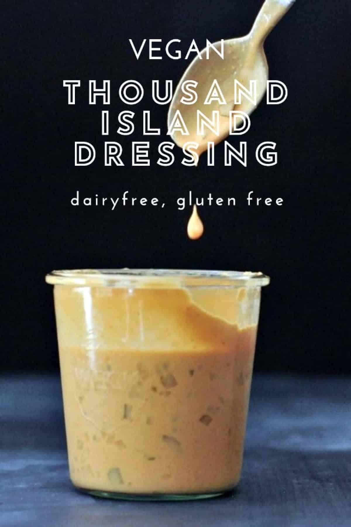 A large glass Weck jar of vegan thousand island dressing, with a spoon dripping sauce above the jar against a black background.