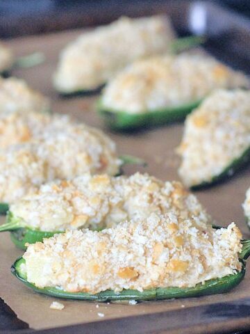 Pineapple jalapeño poppers with cracker breading on a baking sheet.