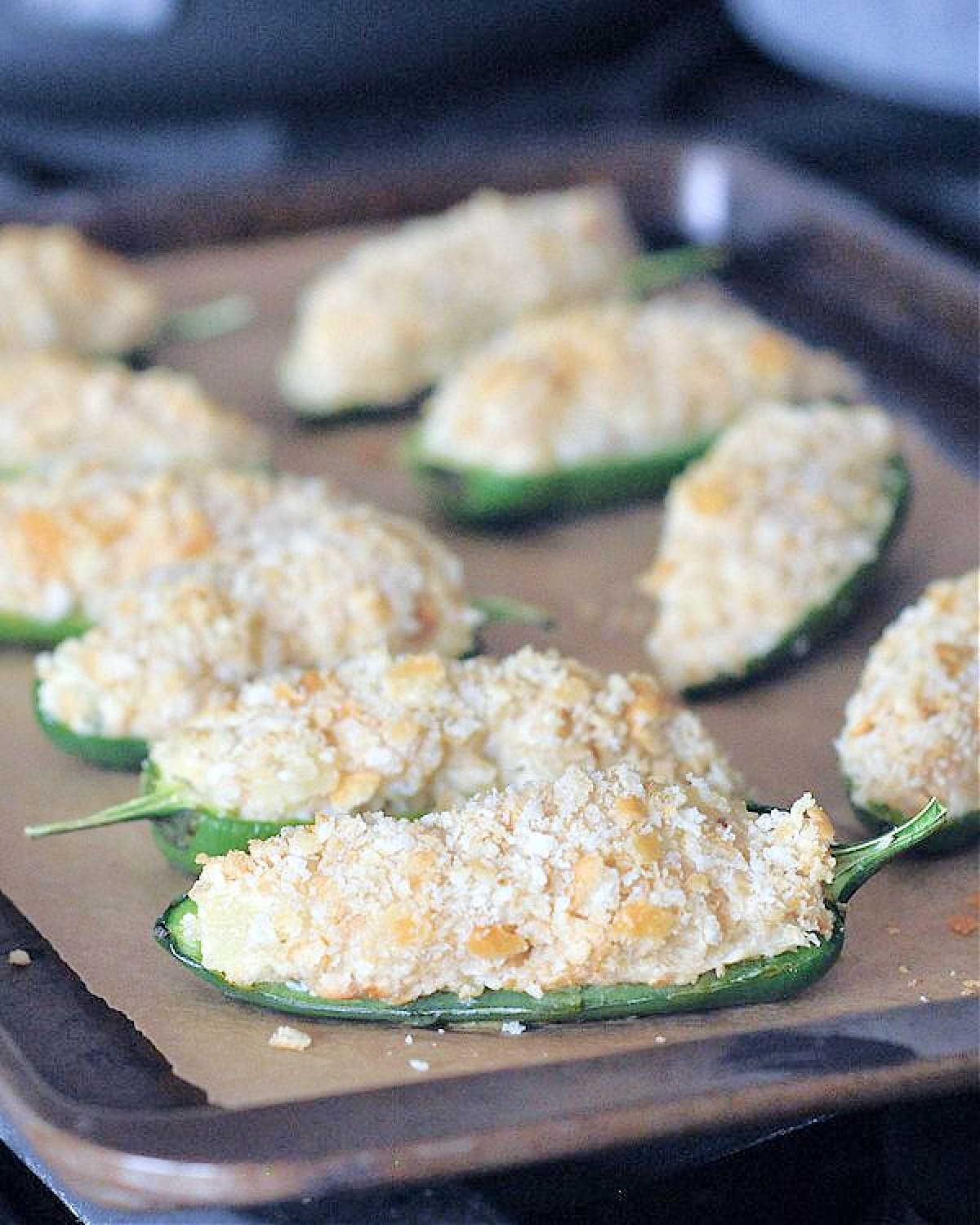 Pineapple jalapeño poppers with cracker breading on a baking sheet.