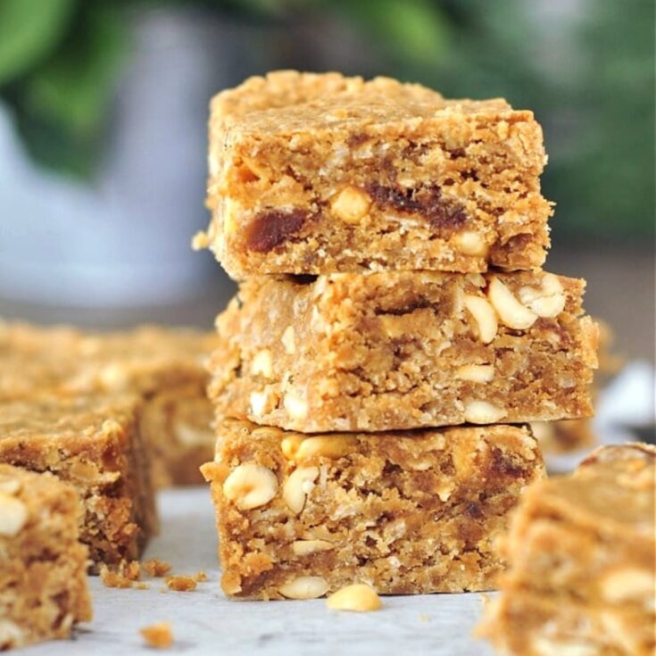 Vegan peanut butter bars on a cutting board, three squares stacked.