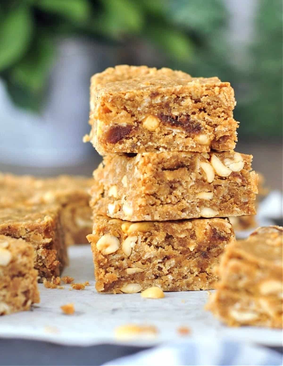 Vegan peanut butter bars on a cutting board, three squares stacked.