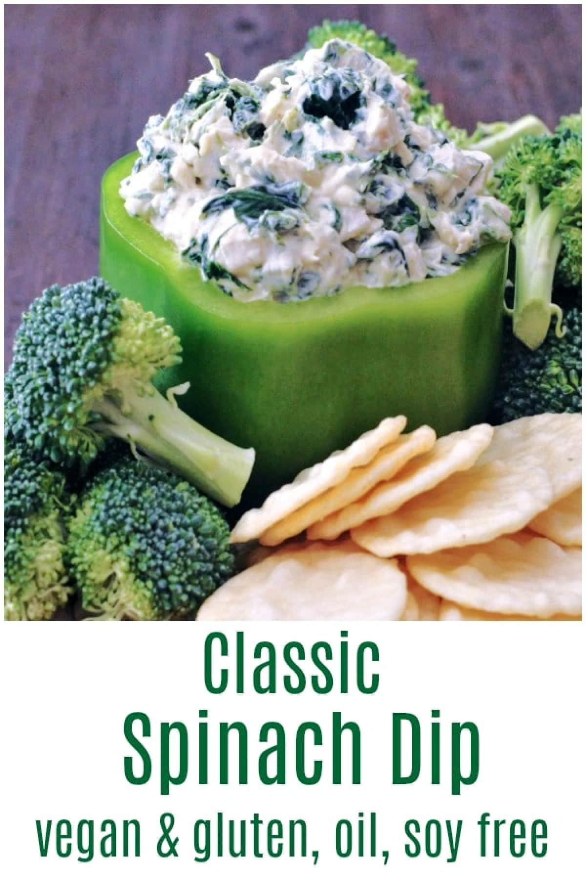 Spinach dip served in a hollowed out green bell pepper, with fresh broccoli trees and rice crackers for dipping.