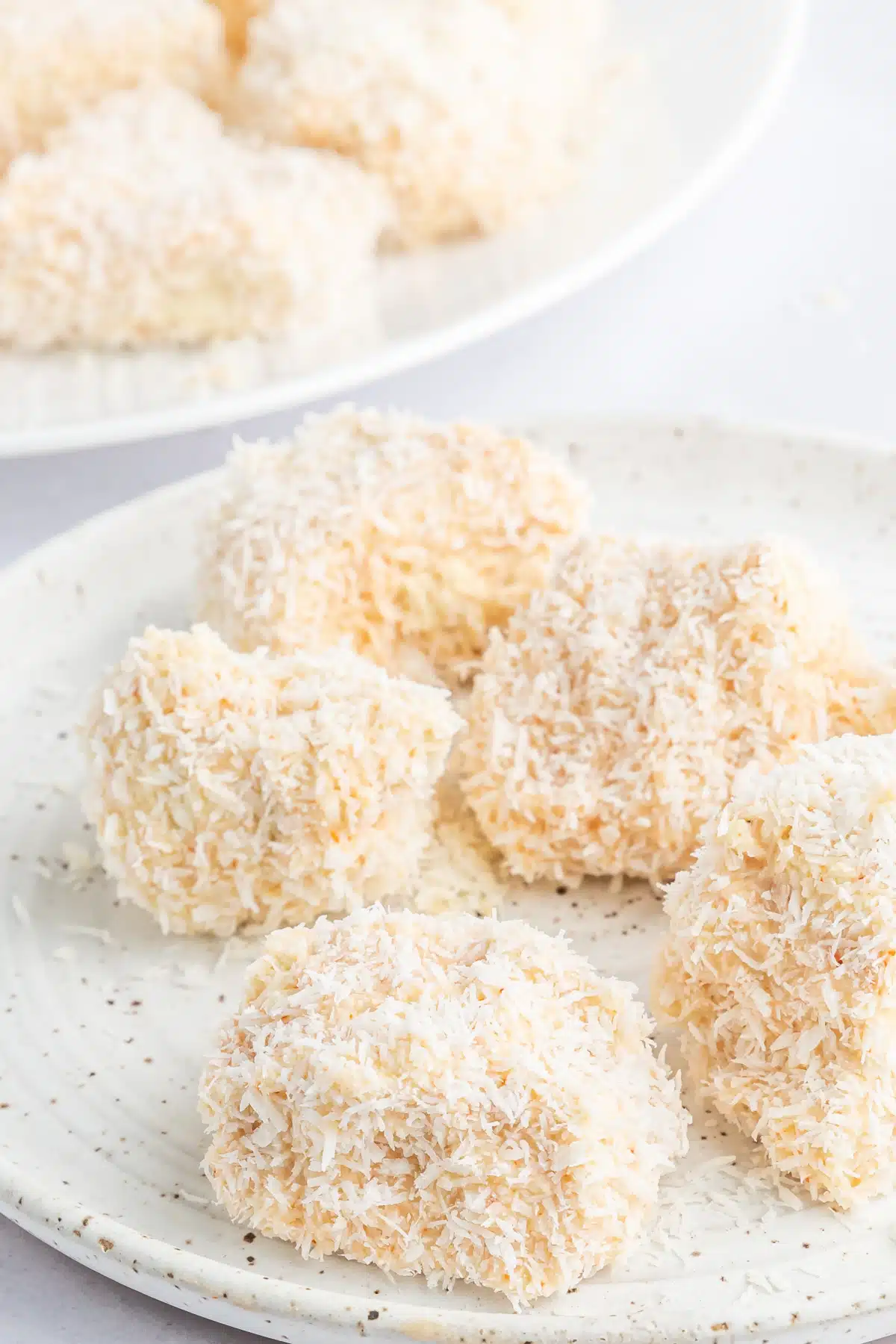 A rustic white plate of crispy breaded tofu before baking.