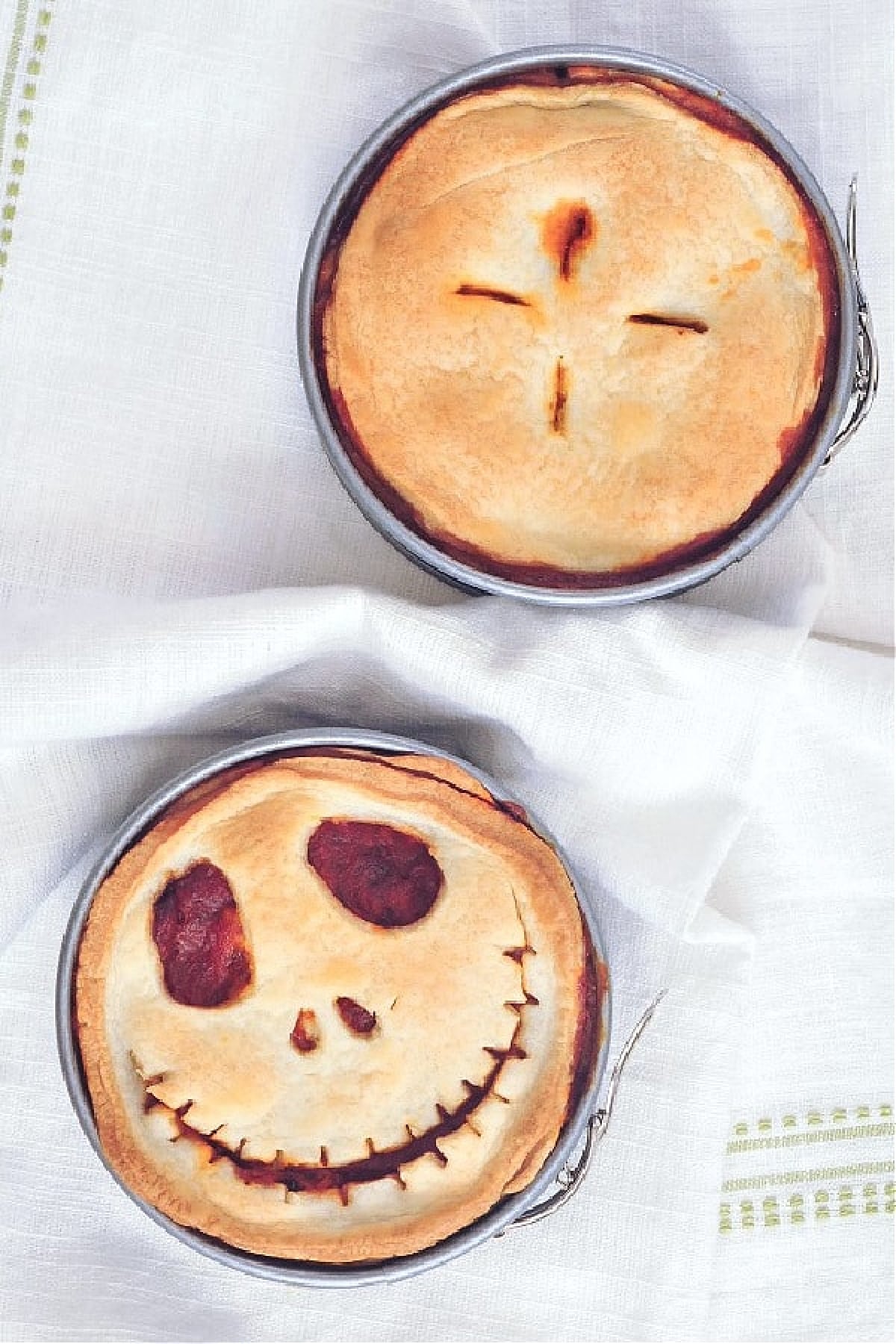 An overhead view of a mini pizza pot pie in a springform pan, the top of the pie cut into a Halloween Jack Skellington skeleton face.