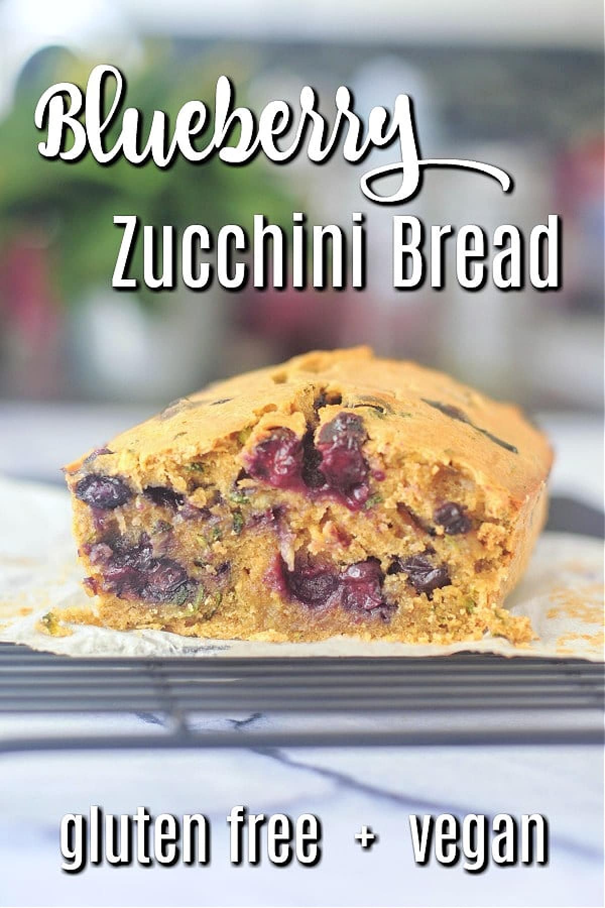 A loaf of blueberry zucchini bread on a wire cooling rack.