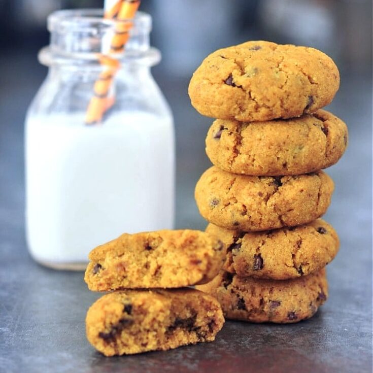 Soft gluten free pumpkin cookies in a stack, next to a short bottle of almond milk with striped straws.