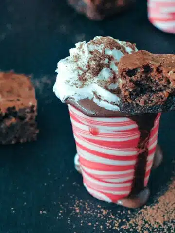 Hot chocolate peppermint shots: hot chocolate in an edible peppermint candy shot glass, topped with whip cream and a small brownie square.