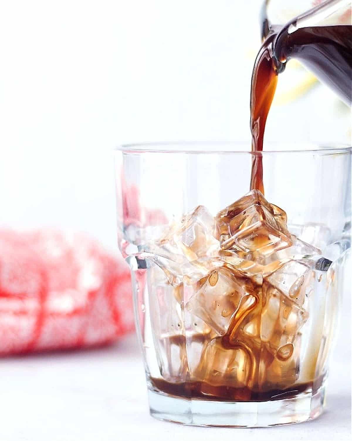 Coconut cold brew coffee being poured into a glass over ice.