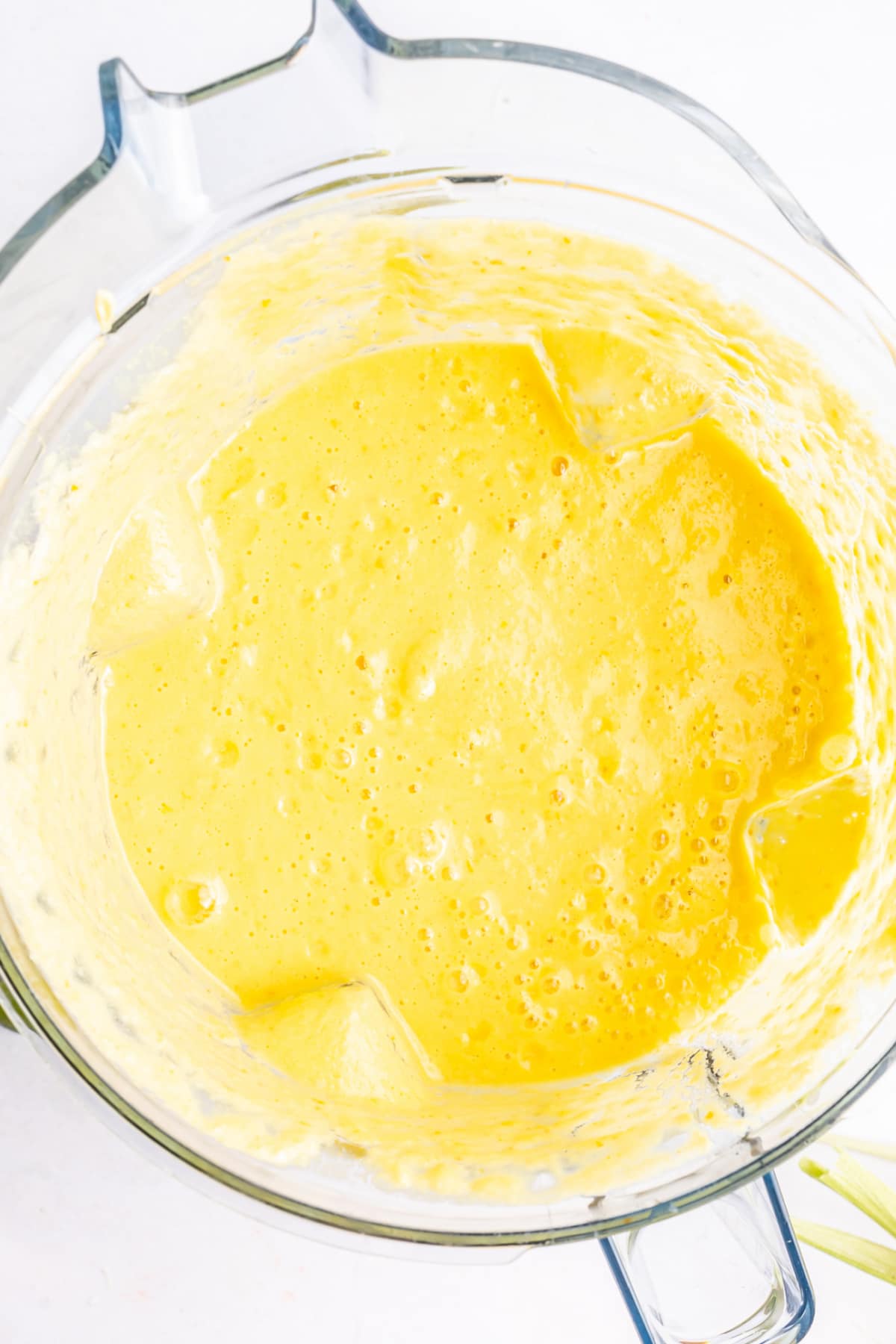 Overhead view of bright yellow summer corn gazpacho in a blender jar after blending.