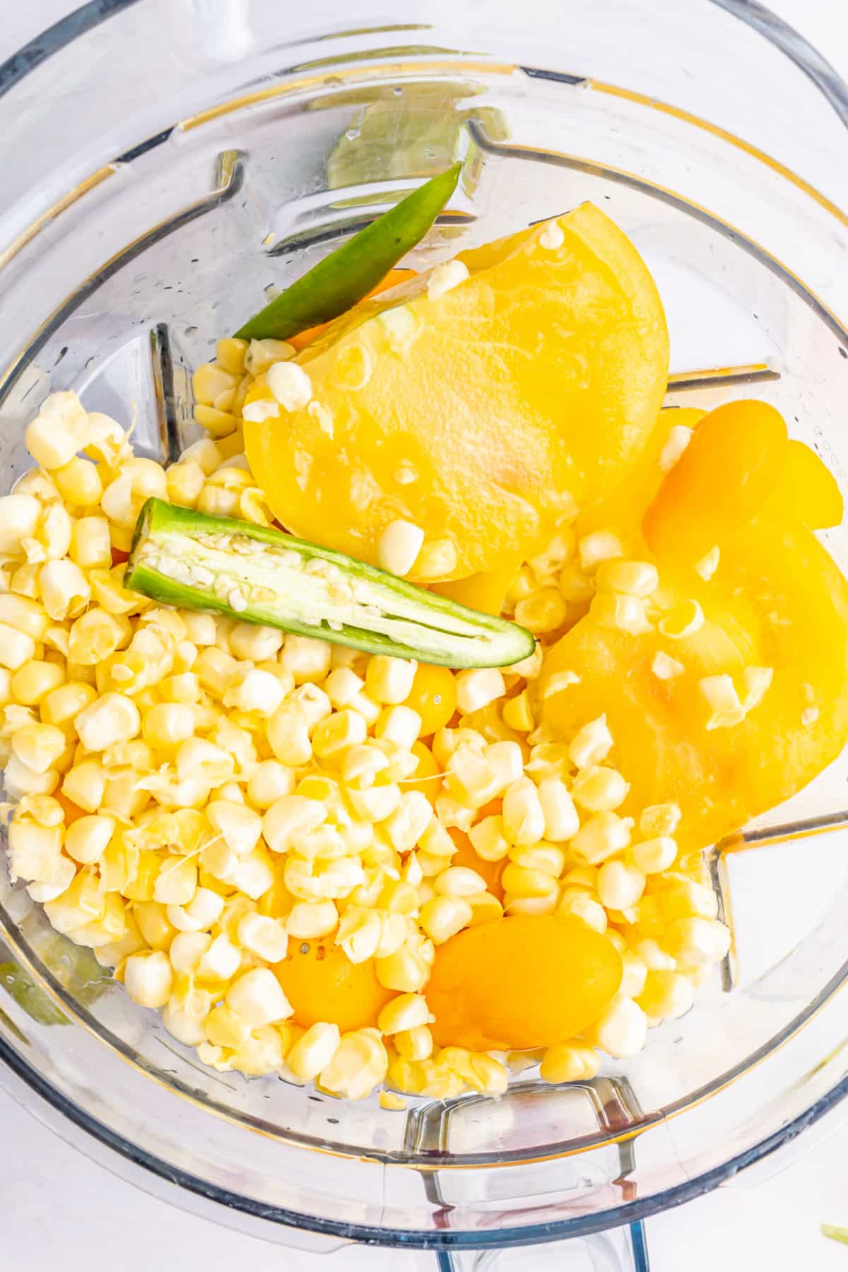 Overhead view of summer corn gazpacho ingredients in a blender jar before blending.