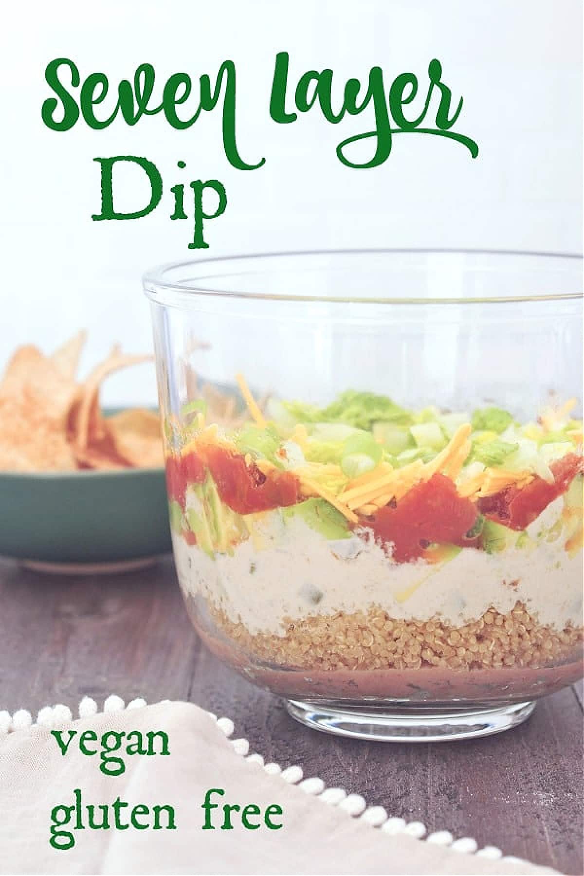 Side view of all the layers in dairy free seven layer dip: beans, quinoa, cashew cheese sauce, avocado, tomato, green onions and lettuce.