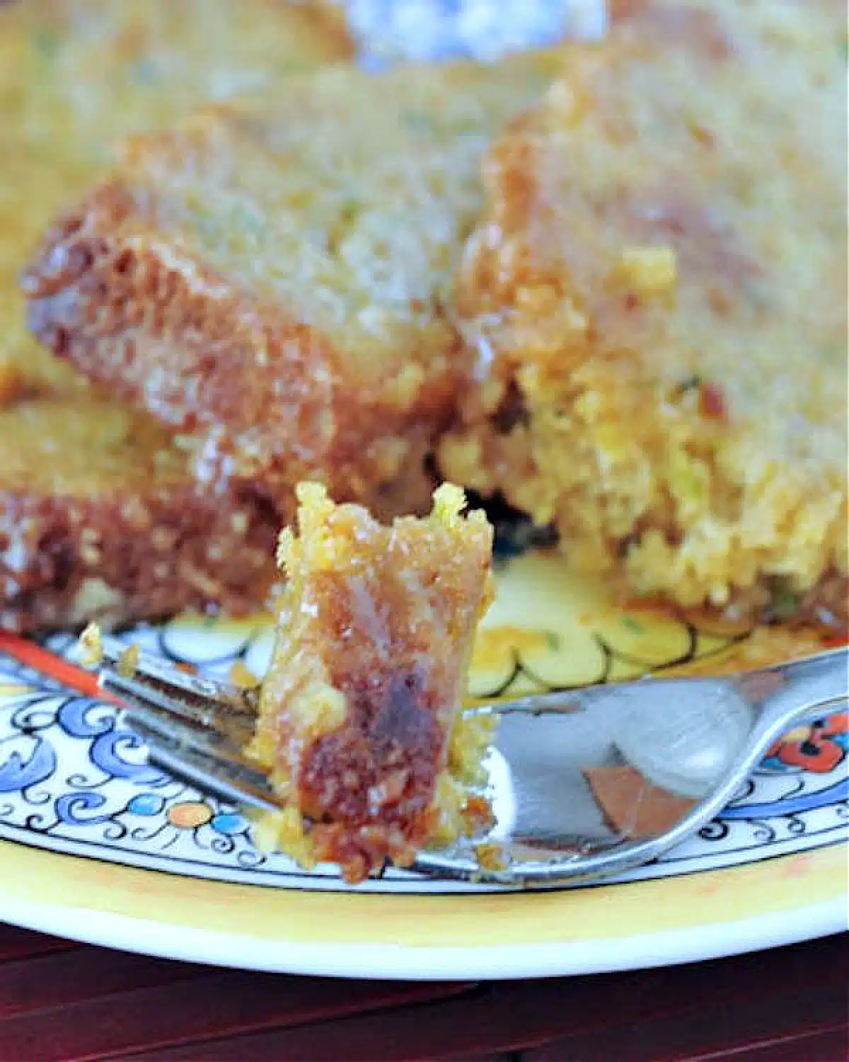 Zucchini bread French toast on an colorful plate, with a fork holding one bite.