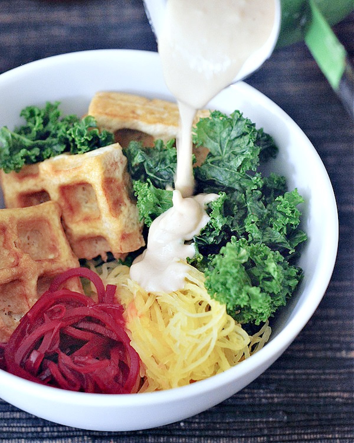 Veggie bowl with waffled tofu (spaghetti squash, roasted beet ribbons, marinated kale, and tofu cooked in the waffle maker) with a tahini sauce drizzled over top.